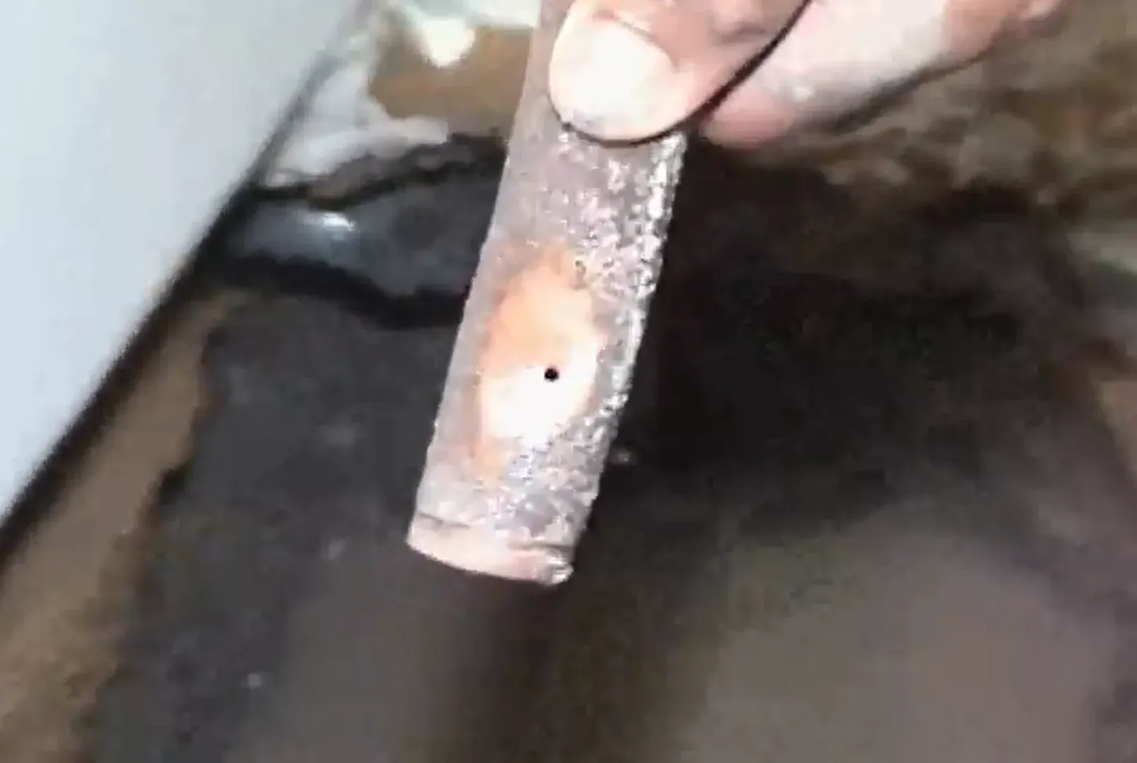 Close-up of a pinhole leak found in a copper slab water line during detection